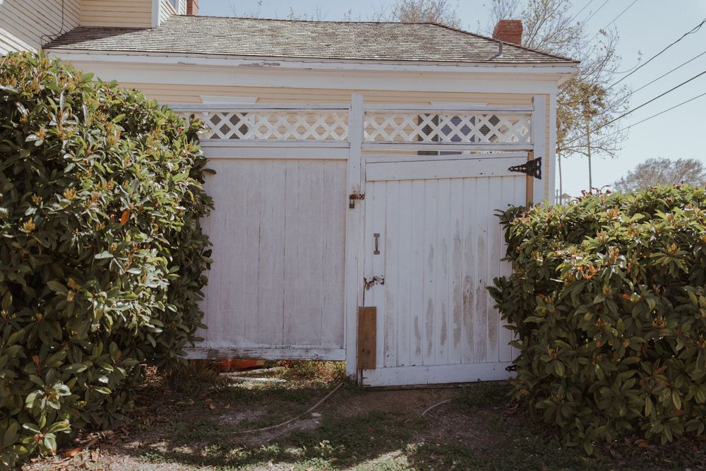 A white wooden lattice fence with ornate details spans across multiple panels in a residential setting.