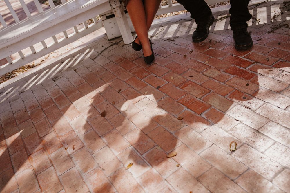 Feet and shadows cast on a red brick patio or walkway during an outdoor gathering.