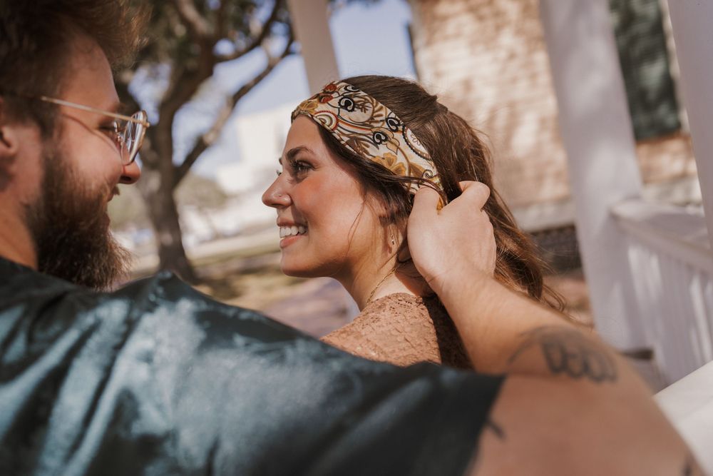 A couple shares an intimate moment during their wedding ceremony while standing under a veil in natural light.