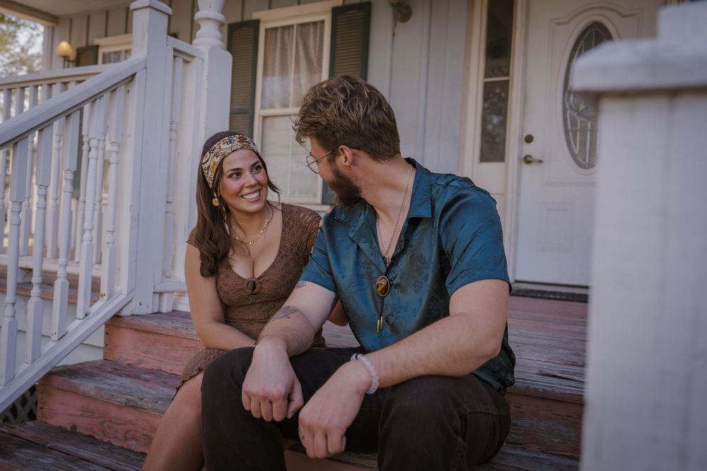 Couple sitting together on porch steps during an intimate outdoor engagement photo session.