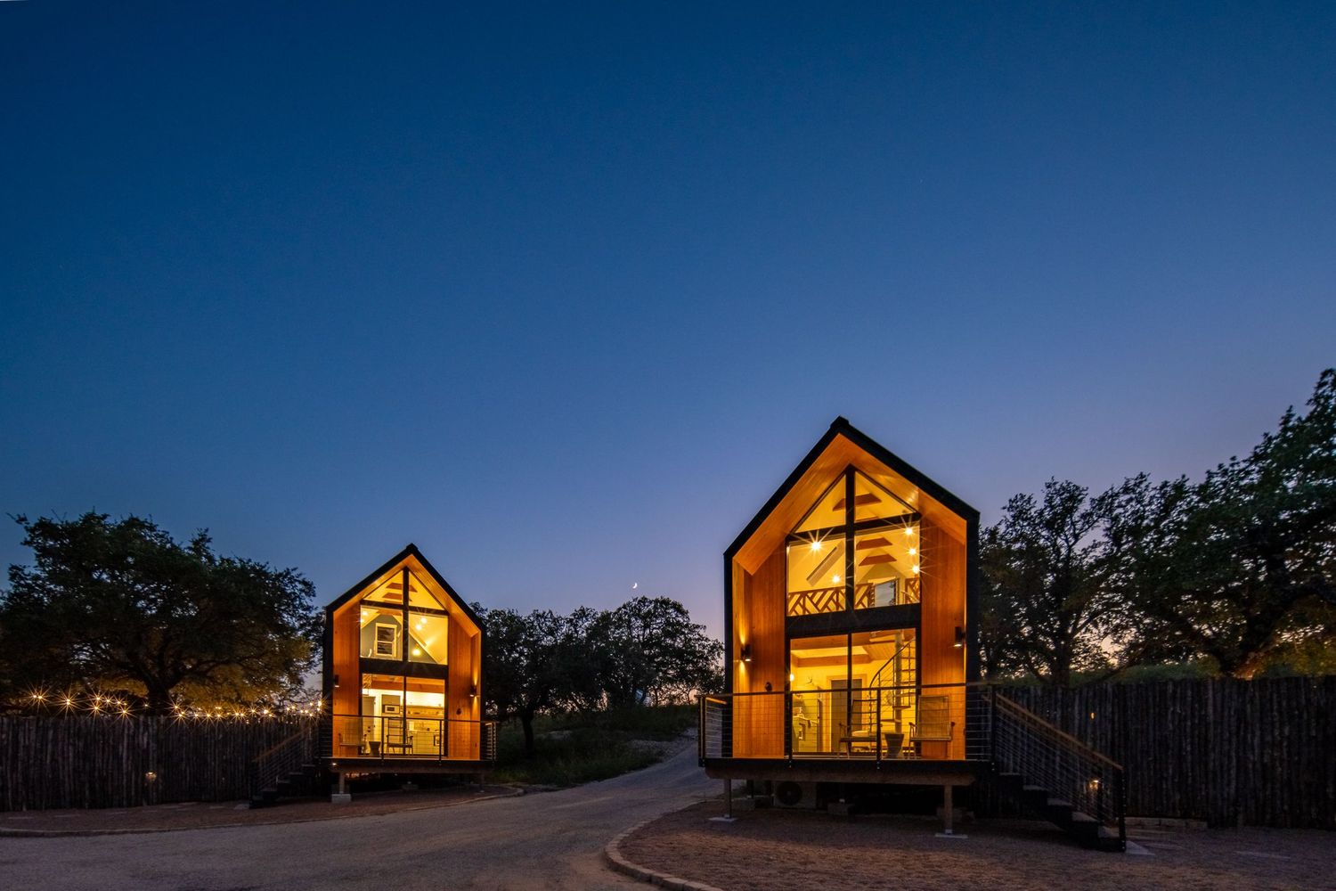 Illuminated A-frame cabins glowing warmly against the dark night sky.