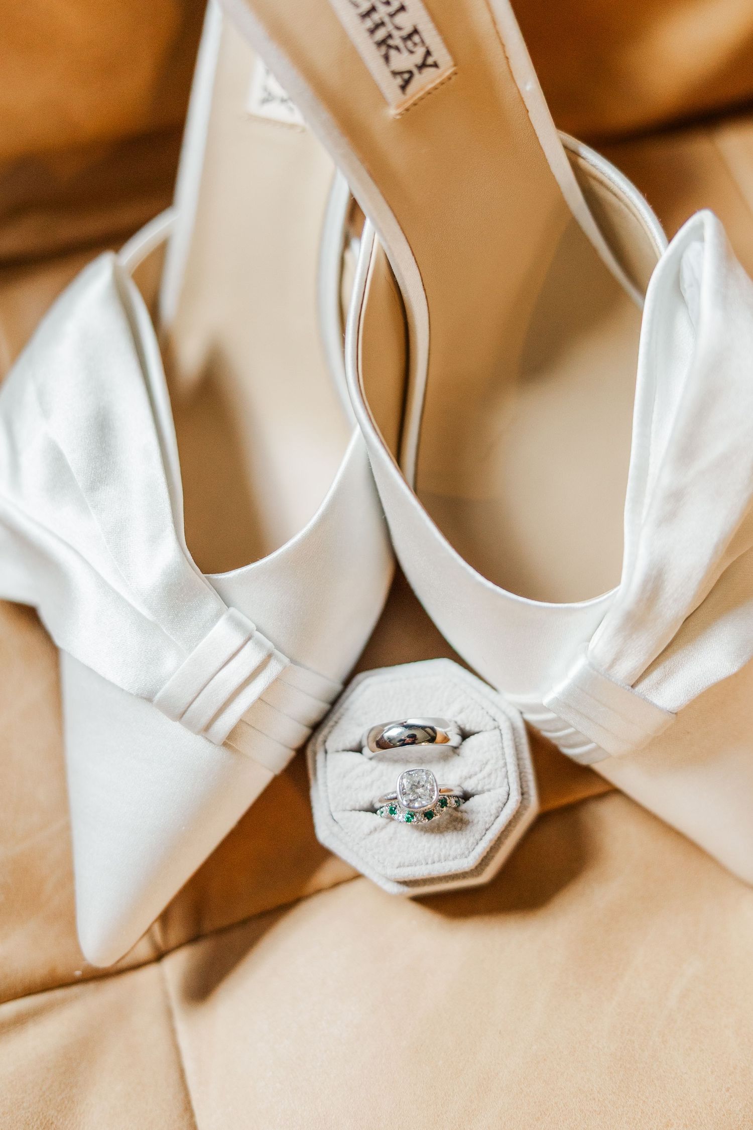 White bridal heels with crystal embellishments arranged in a row on beige surface for wedding photography.