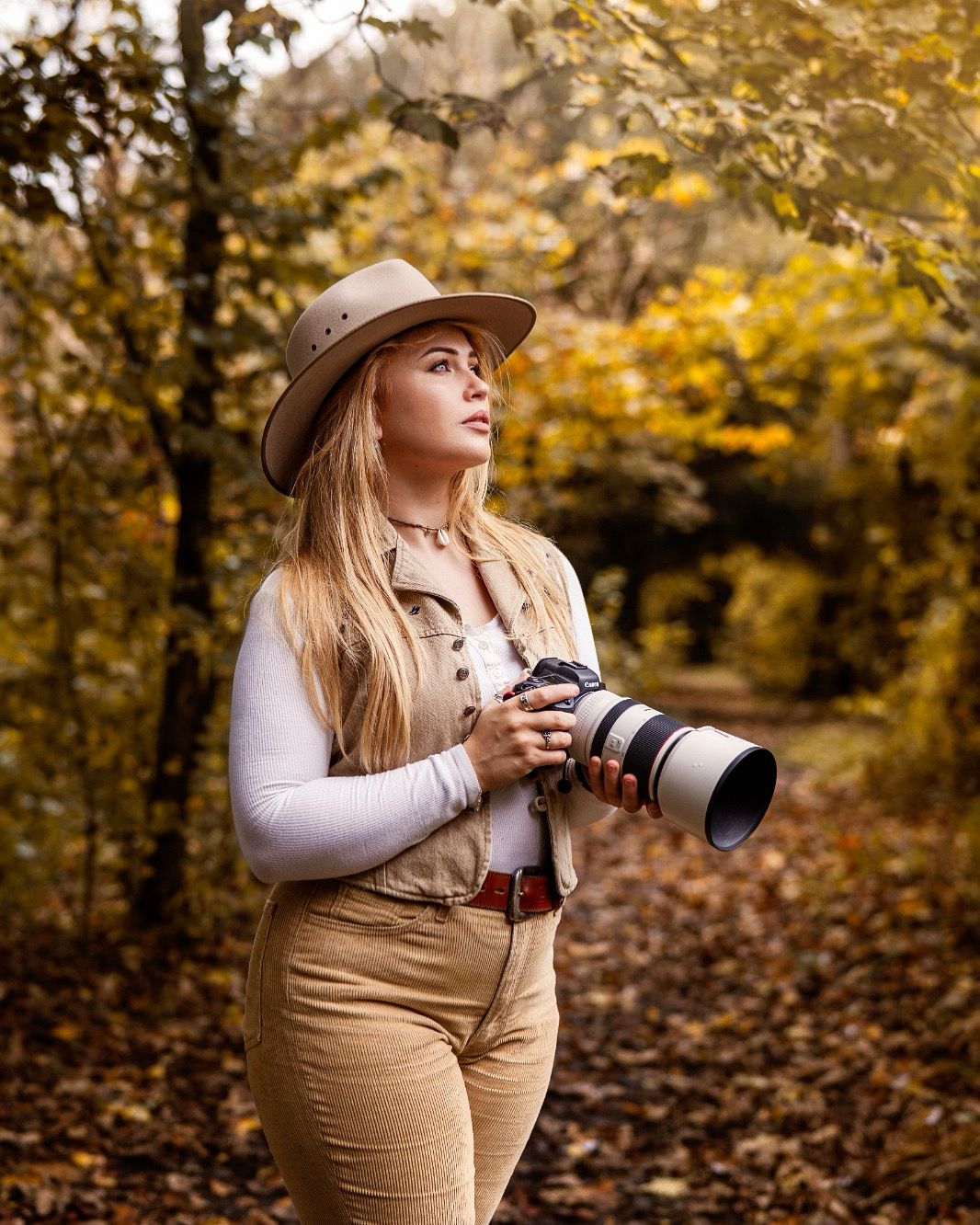 Nature photographer with professional camera exploring autumn forest trail.