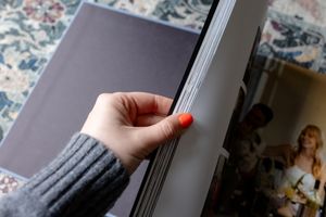Hand holding open a book or magazine against a blurred background.