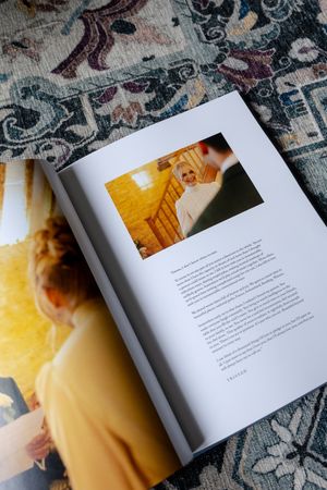 Open book with text pages displayed on patterned fabric background with warm lighting.