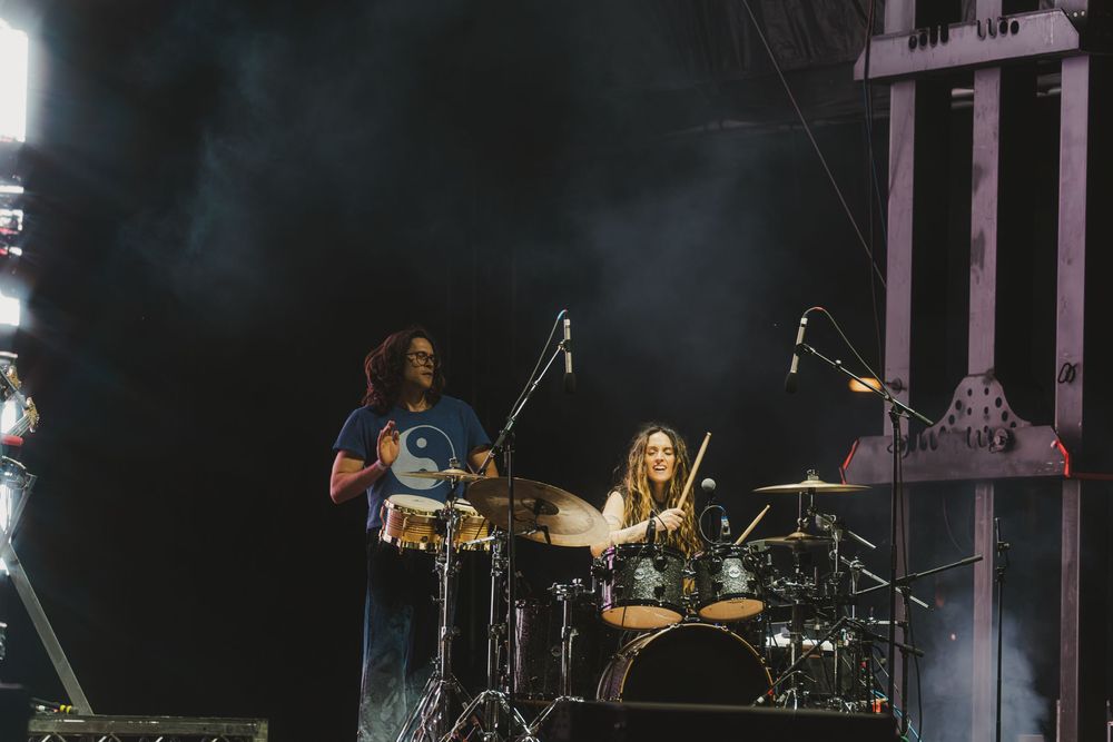 A rock band performs on stage with dramatic lighting and smoke effects during a live concert performance.