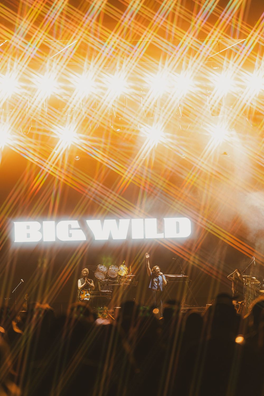 Concert stage with 'BIG WILD' text overlay and dramatic orange lighting creating diagonal streaks across the performance.