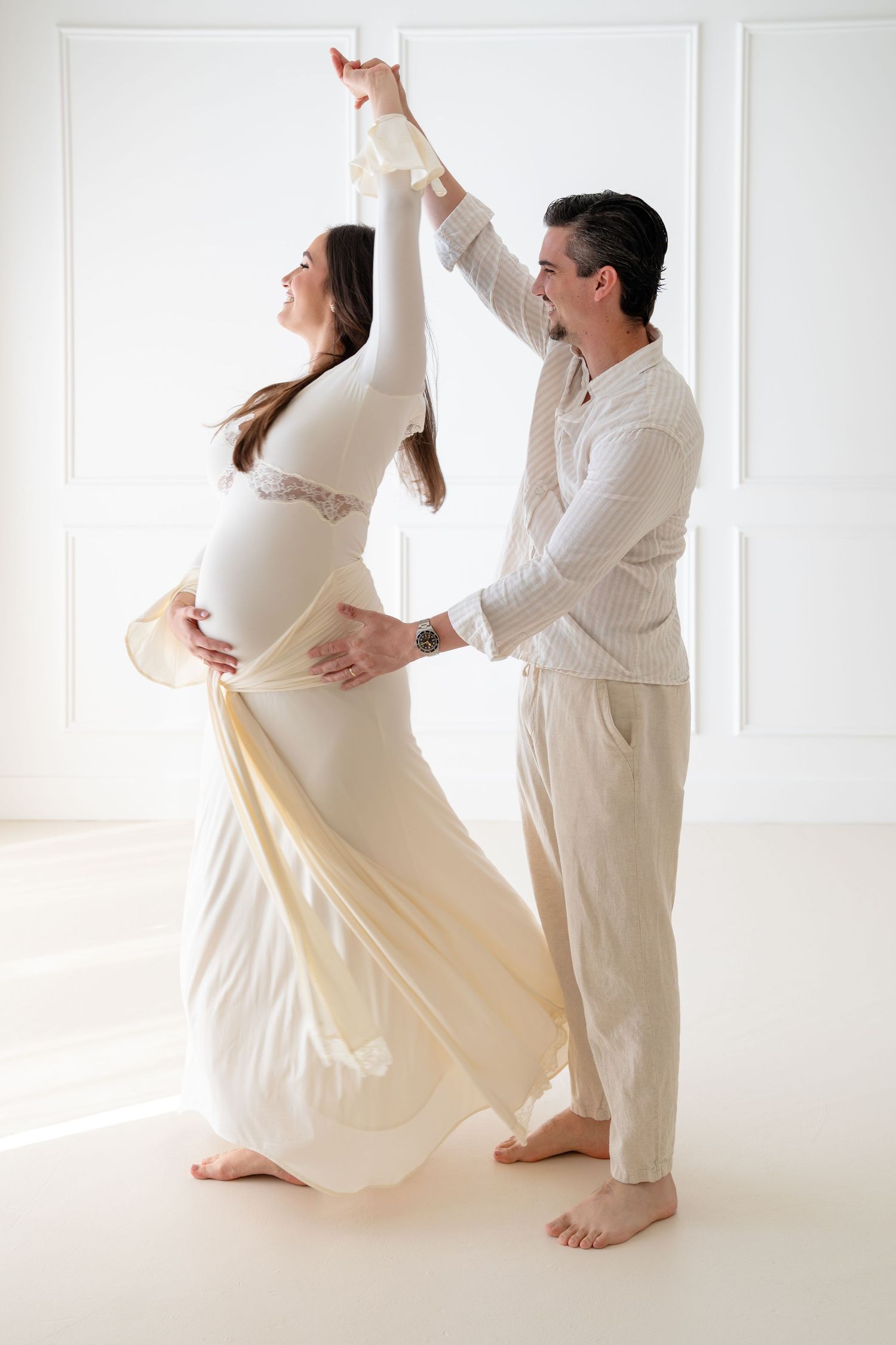 A couple in white outfits performs a flowing dance sequence in a bright studio setting.