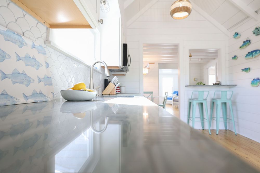 Modern coastal kitchen with concrete countertops and mint green bar stools.