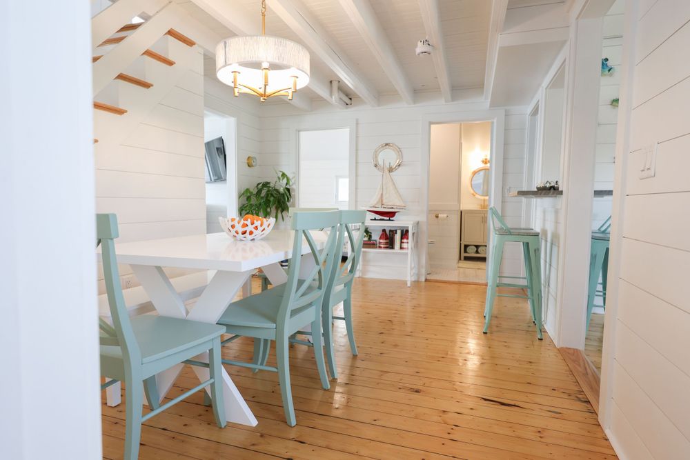 Coastal dining room with mint chairs, wood floors and exposed beam ceiling.