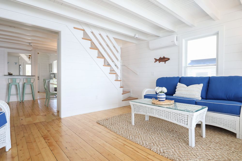 Beach house living room with navy sofa, white walls and natural wood floors.