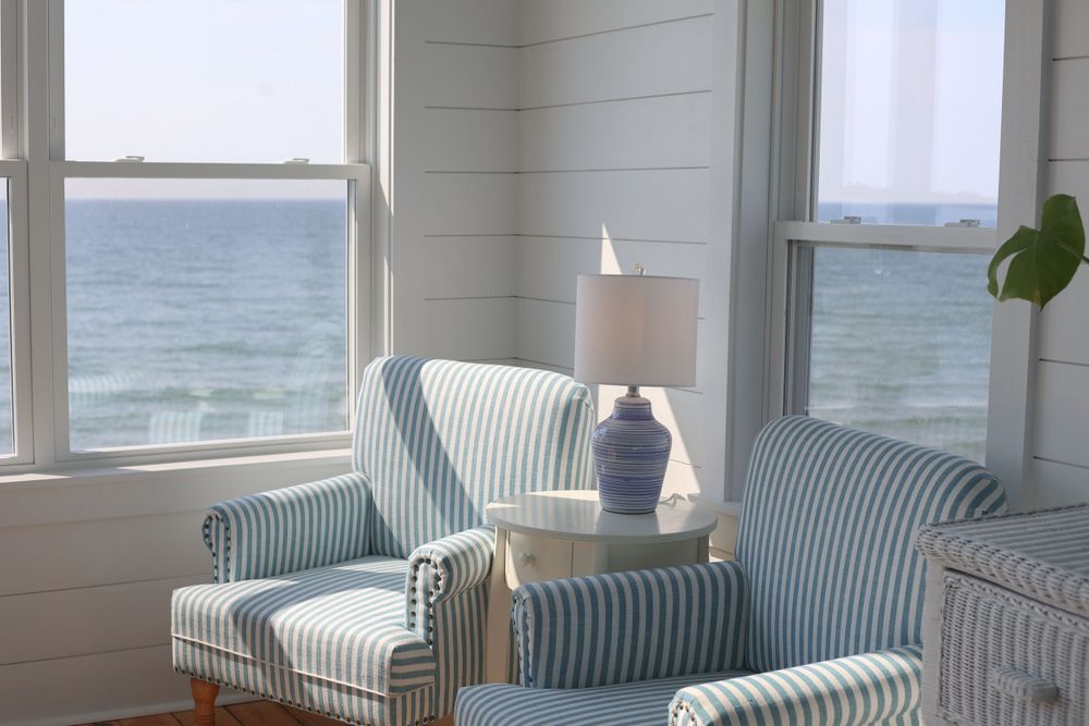 Cozy seating area with striped chairs overlooking the ocean through large windows.
