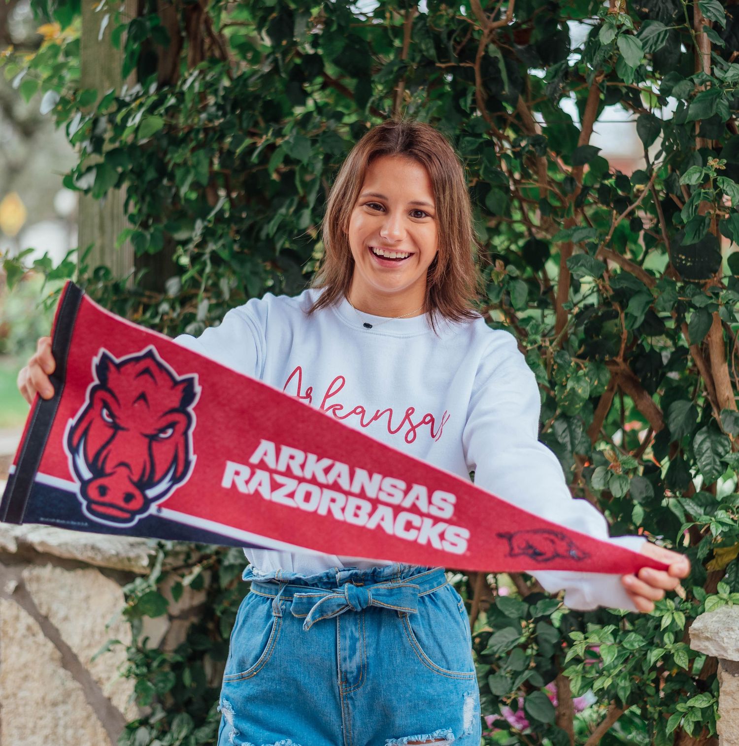 A Houston high school senior posing with her college gear in a scenic park, showcasing her excitement