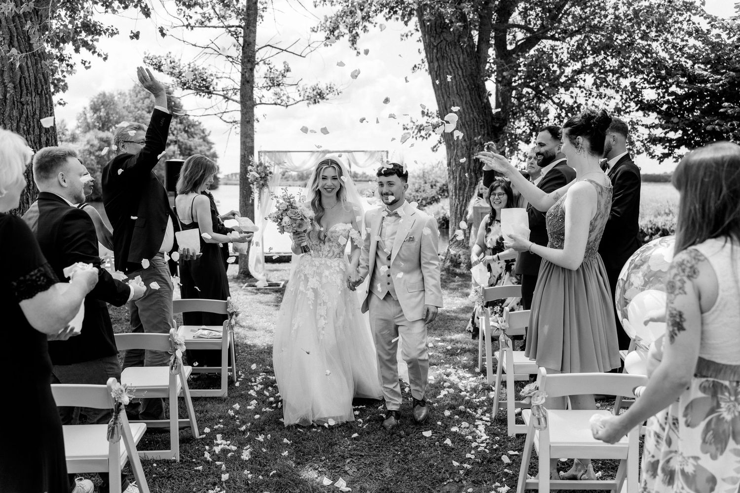 An outdoor wedding ceremony with white chairs and a scenic garden backdrop.