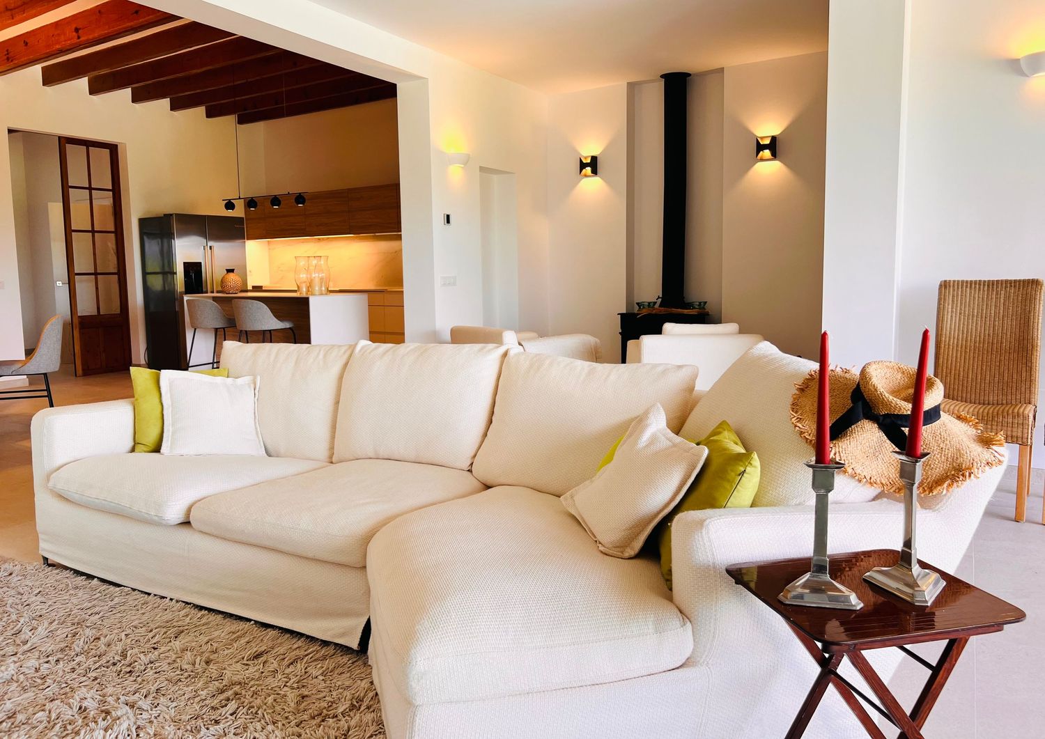 Luxurious white living room interior with modern furniture and exposed wooden beams on the ceiling.