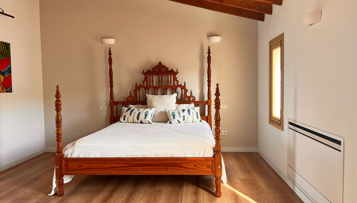 Elegant bedroom with four-poster wooden bed frame and exposed wooden ceiling beams.