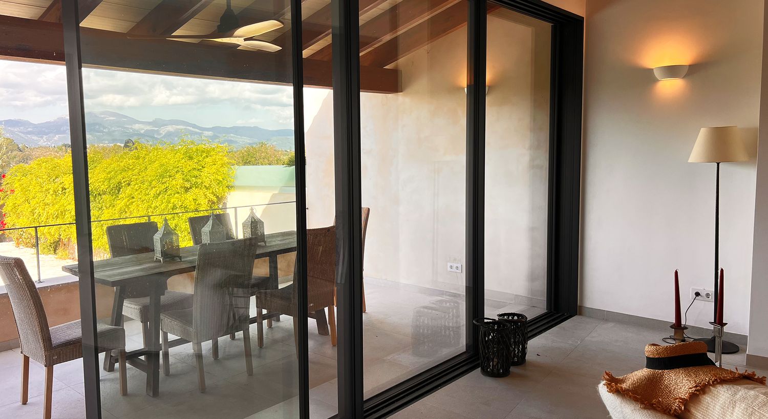 Elegant covered terrace dining area with glass doors overlooking mountain landscape.