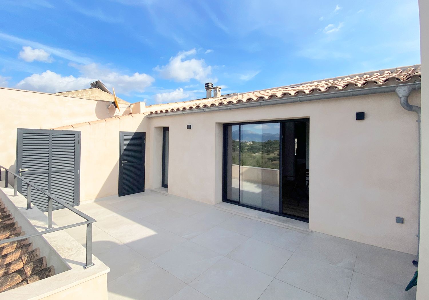 Contemporary terrace with sliding glass doors and metal railings on Mediterranean style building.
