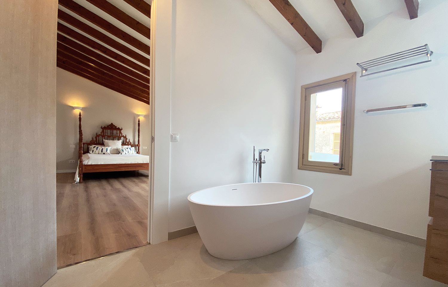 Luxurious freestanding bathtub in minimalist bathroom with wooden ceiling beams and natural light.