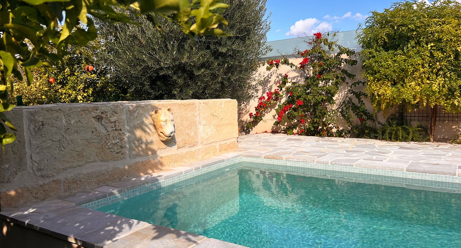 Contemporary pool design with stone walls and water features in a landscaped garden setting.