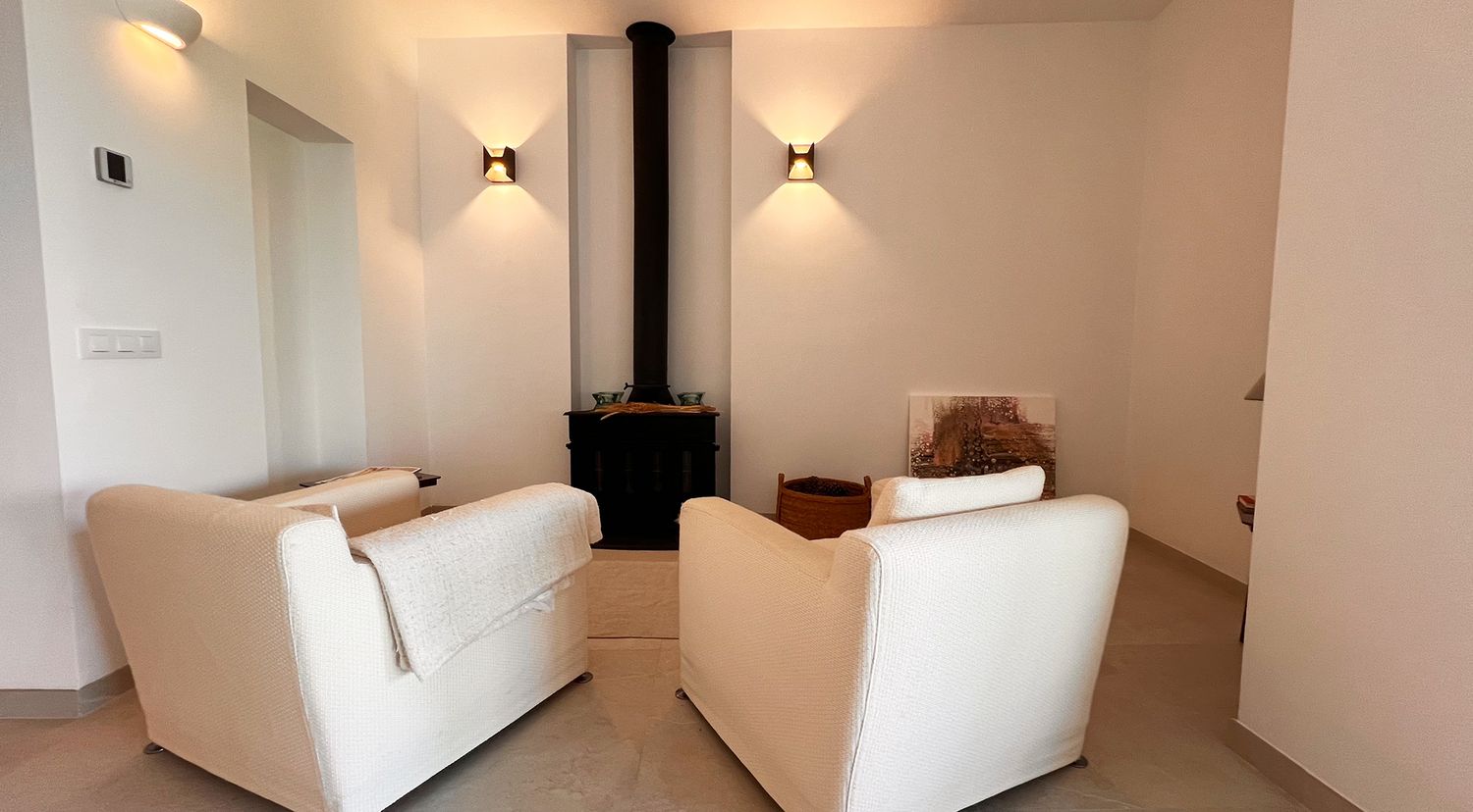 Cozy living room with white armchairs and modern wood burning stove.