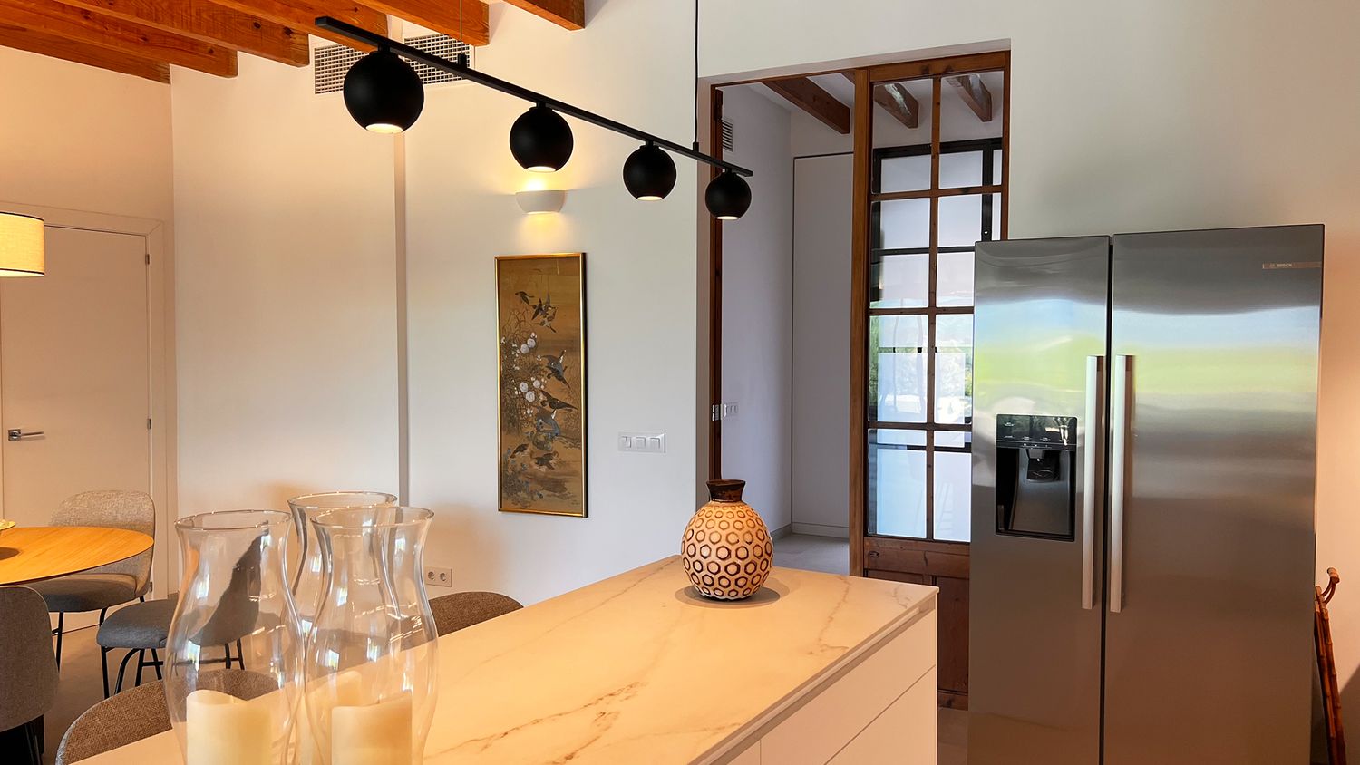 Kitchen island with glass decor and track lighting under exposed wooden beams.
