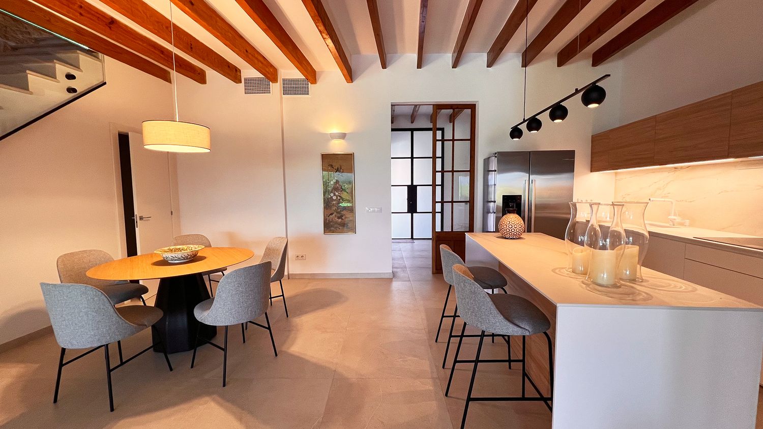 Modern open concept dining and kitchen area with exposed wooden beams and contemporary furniture.