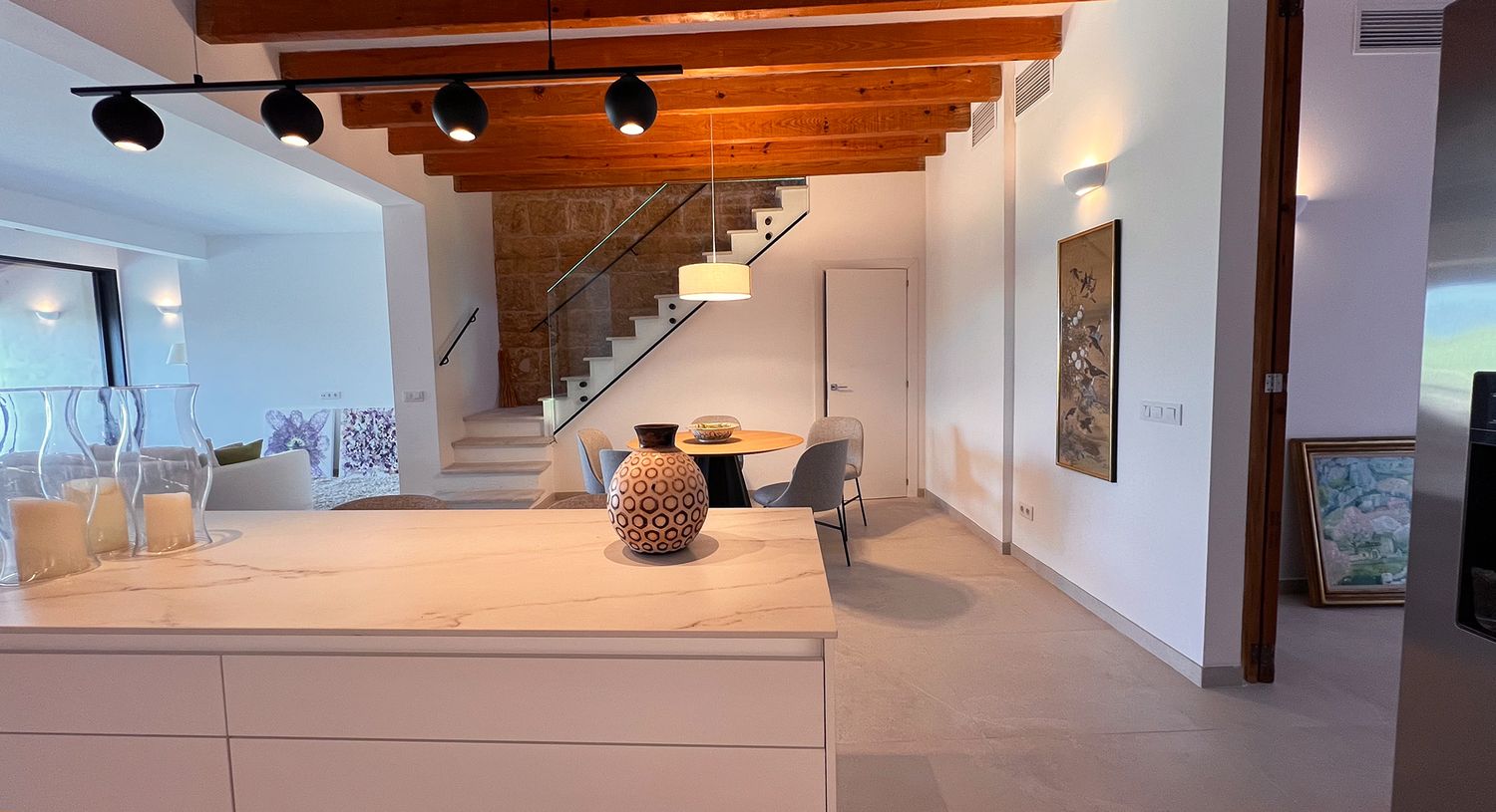 Modern interior featuring white floors, wooden ceiling beams, and minimalist furniture arrangement.