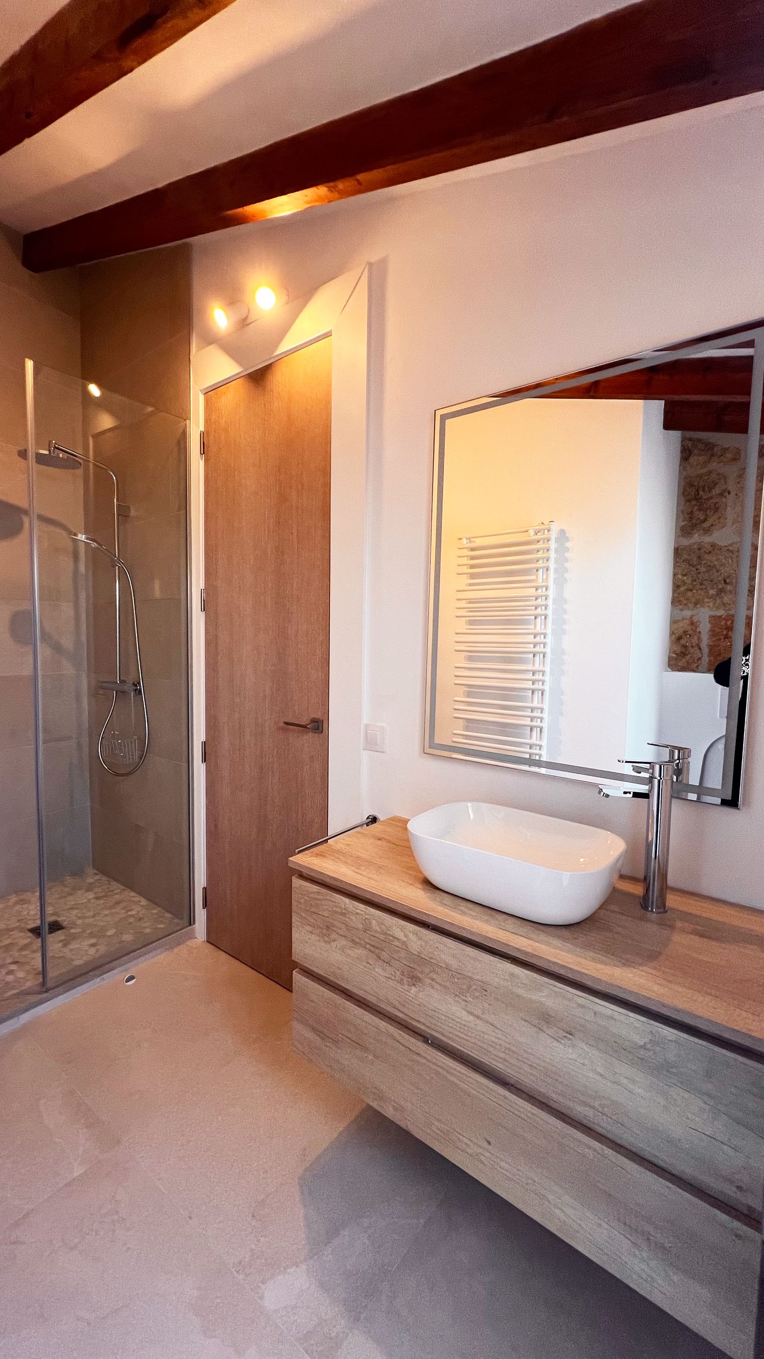 Contemporary bathroom with vessel sink, wooden vanity and glass shower enclosure.