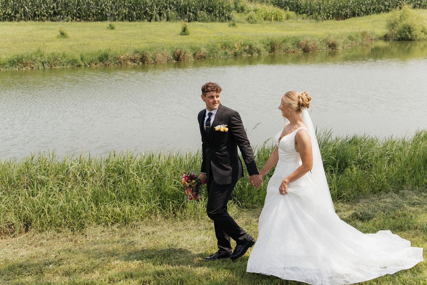 Wedding party poses together on a sunny lawn in formal attire.