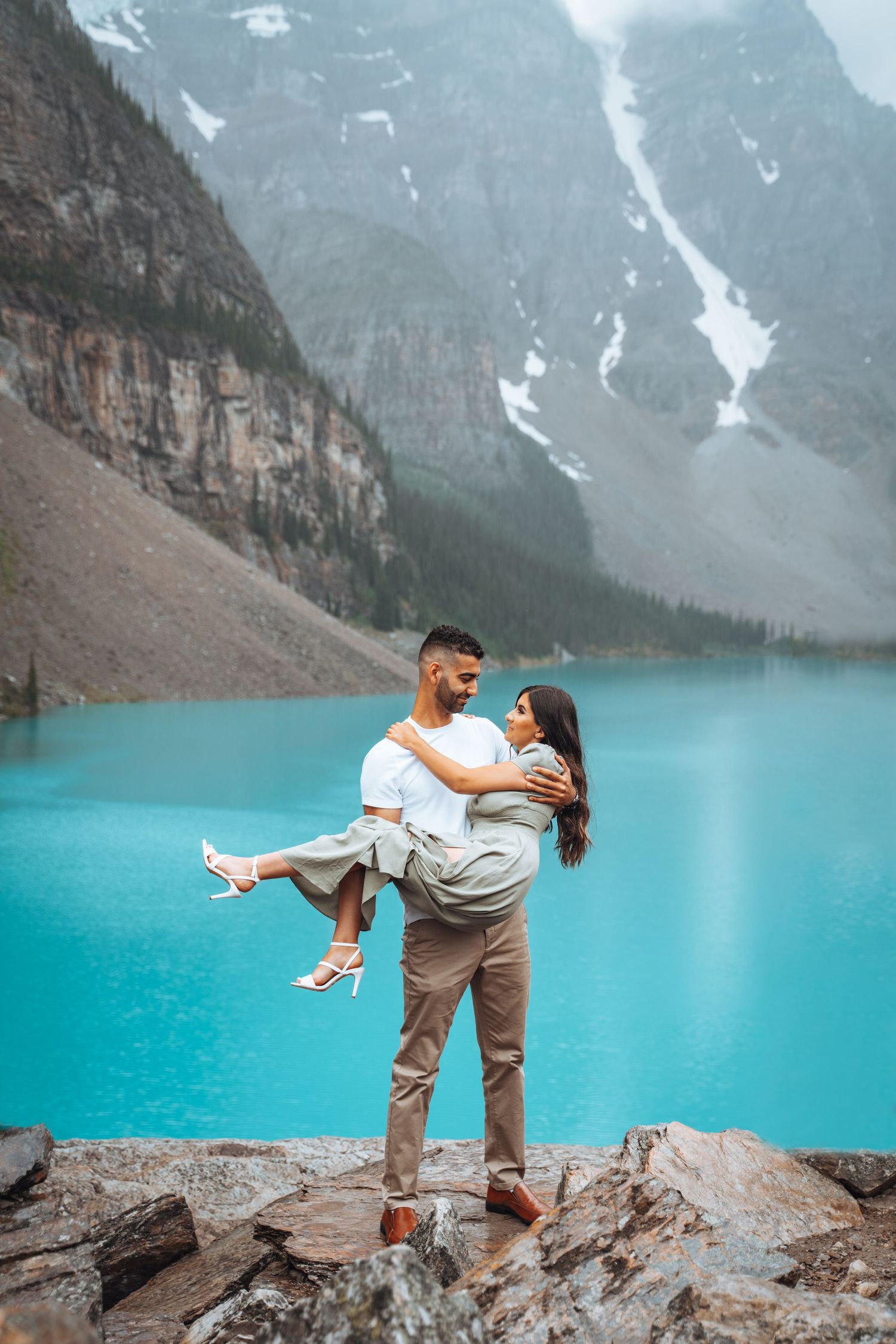 Groom carries the bride by Moraine Lake. Banff engagement photography.