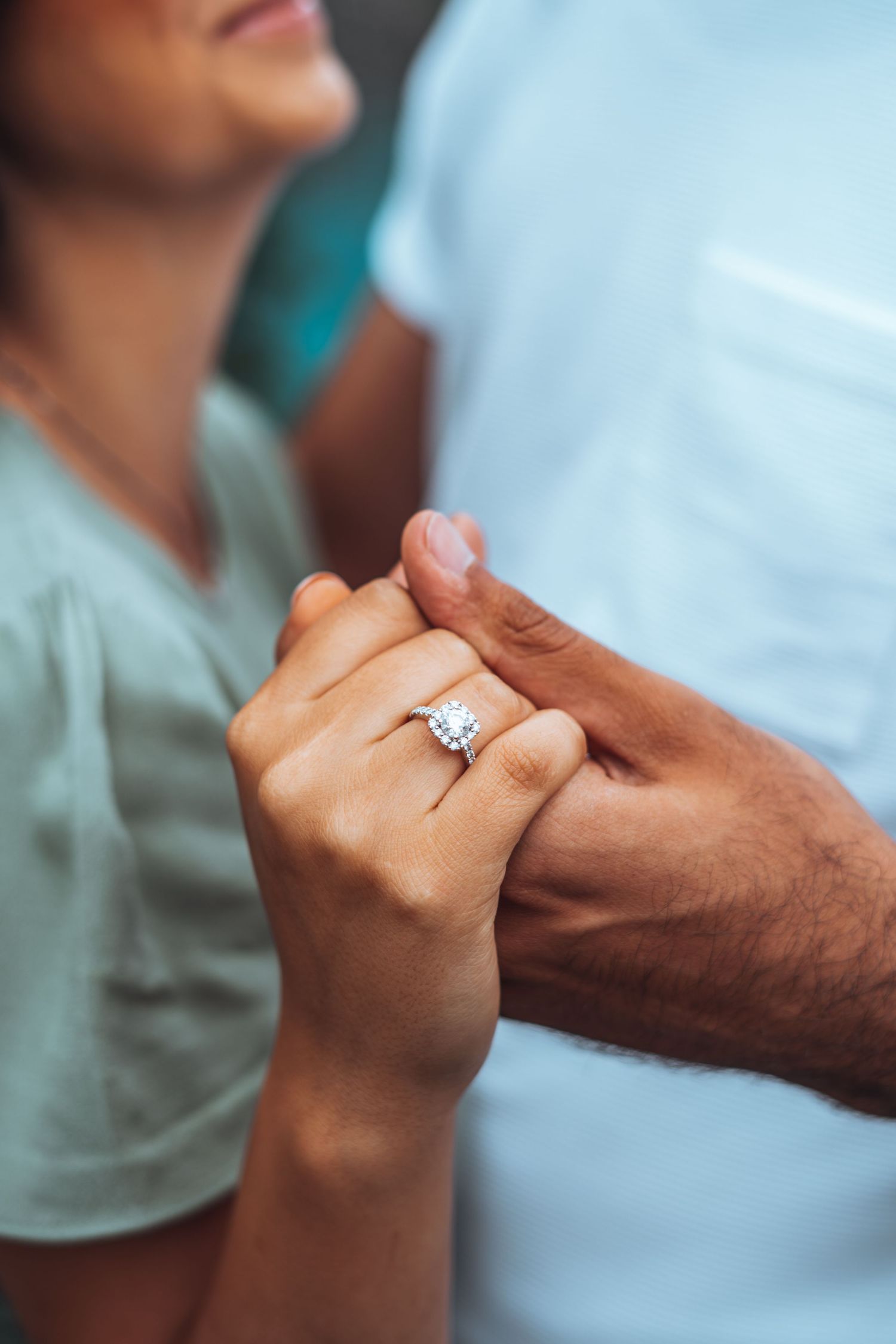 Close up of a bride's hand holding her fiancé's hand, showcasing a stunning diamond engagement ring. Calgary engagement.