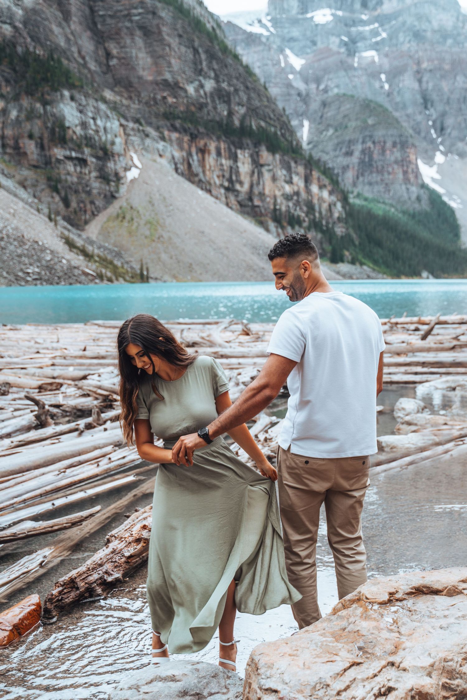 Couple walking on logs by Moraine Lake. Banff engagement photography.