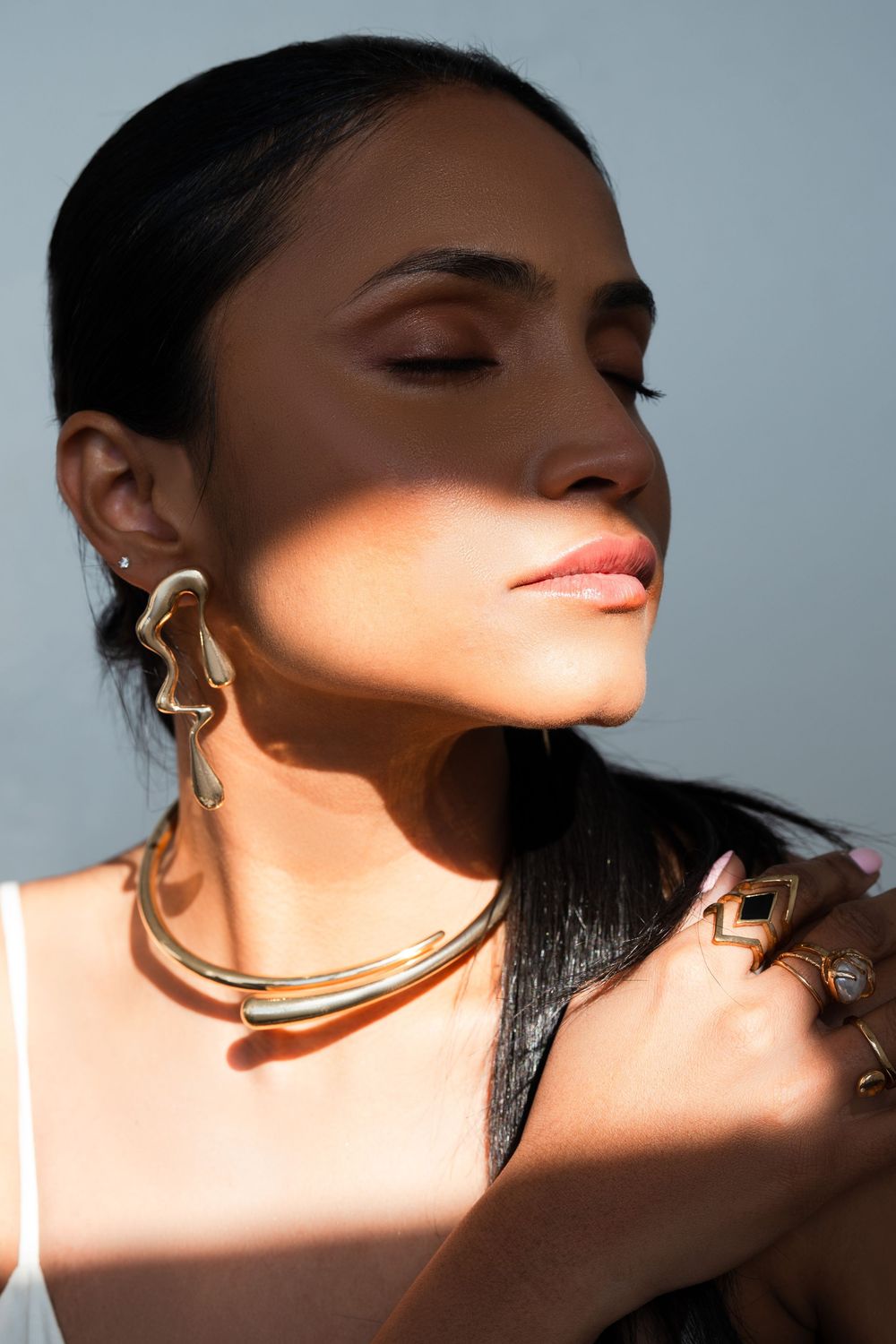 A dramatic profile view sequence in warm lighting shows golden jewelry against dark hair and soft skin tones.