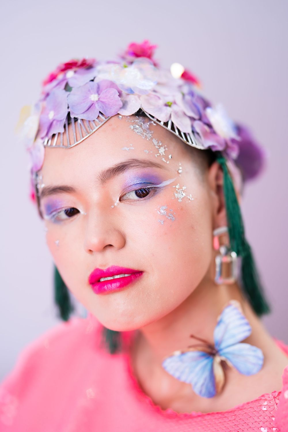 Ethereal beauty shot with butterfly details, pink lips, and floral crown in pastel tones.