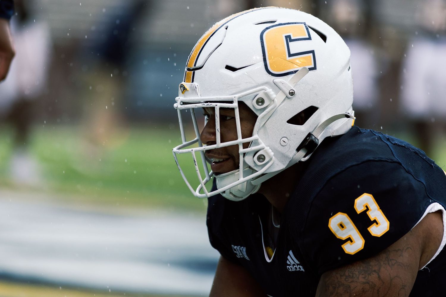 Close-up view of a Chattanooga football player wearing a white helmet with gold 'C' logo and number 93 jersey.