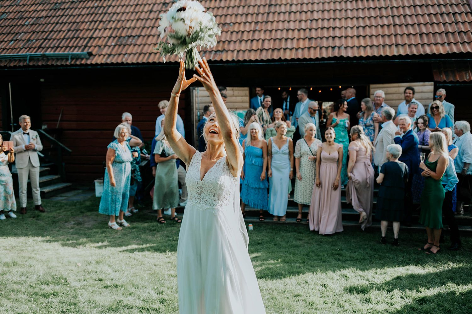 Malin och Olas bröllop vid Forshaga hembygdsgård.   Bröllopsfotograf i Karlstad Rebecca Nordin. Brudbuketten kastas.