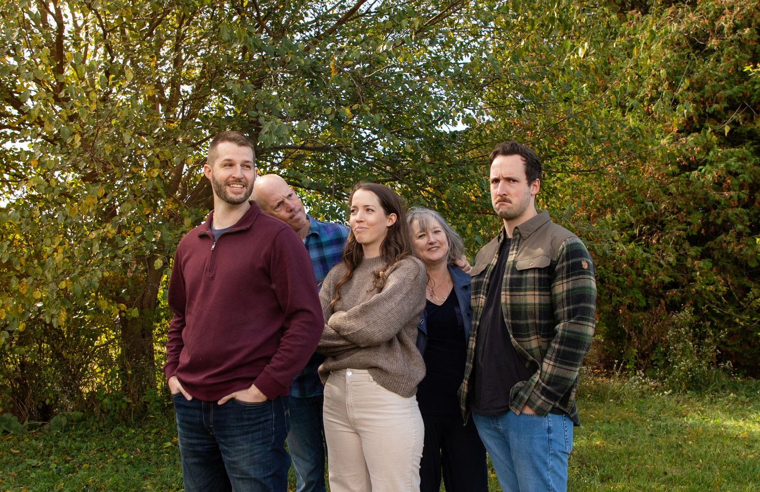 An adult grown family with the two younger adult children making grumpy faces and the parents making confused faces looking at them