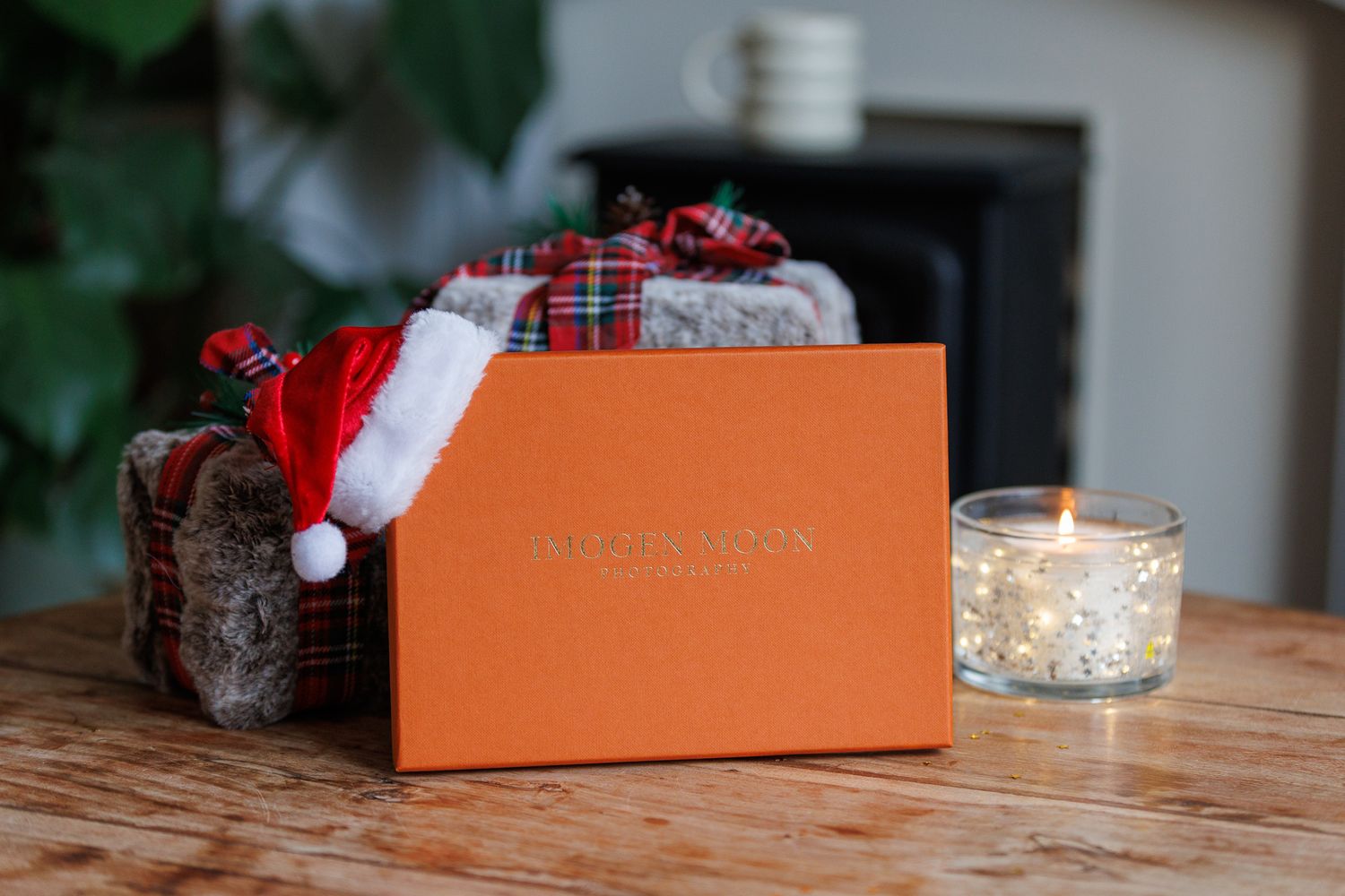 A festive holiday scene with wrapped presents, candles, and decorative boxes arranged on a wooden table.