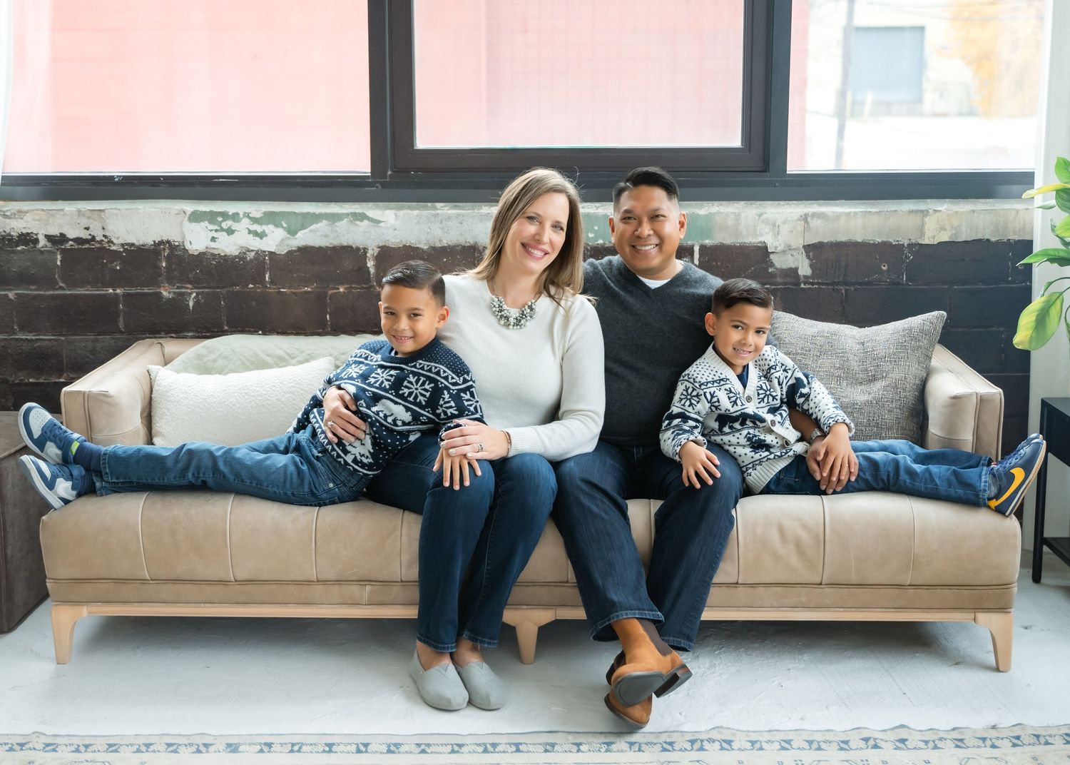 Couple lounging on a modern gray couch in a bright living room wearing matching socks and jeans.