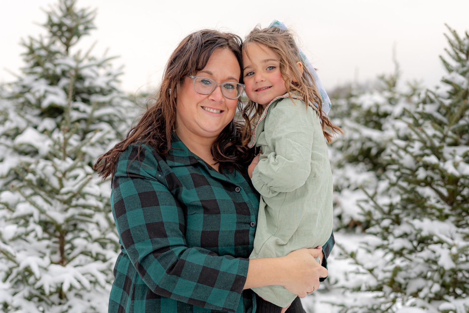Winter family portraits with snow-covered evergreen trees in the background.