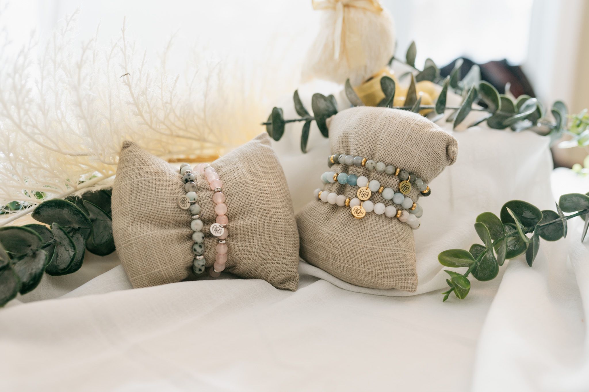 Rustic wedding decor with burlap wrapped mason jars, floral accents and green ivy garland on white surface.