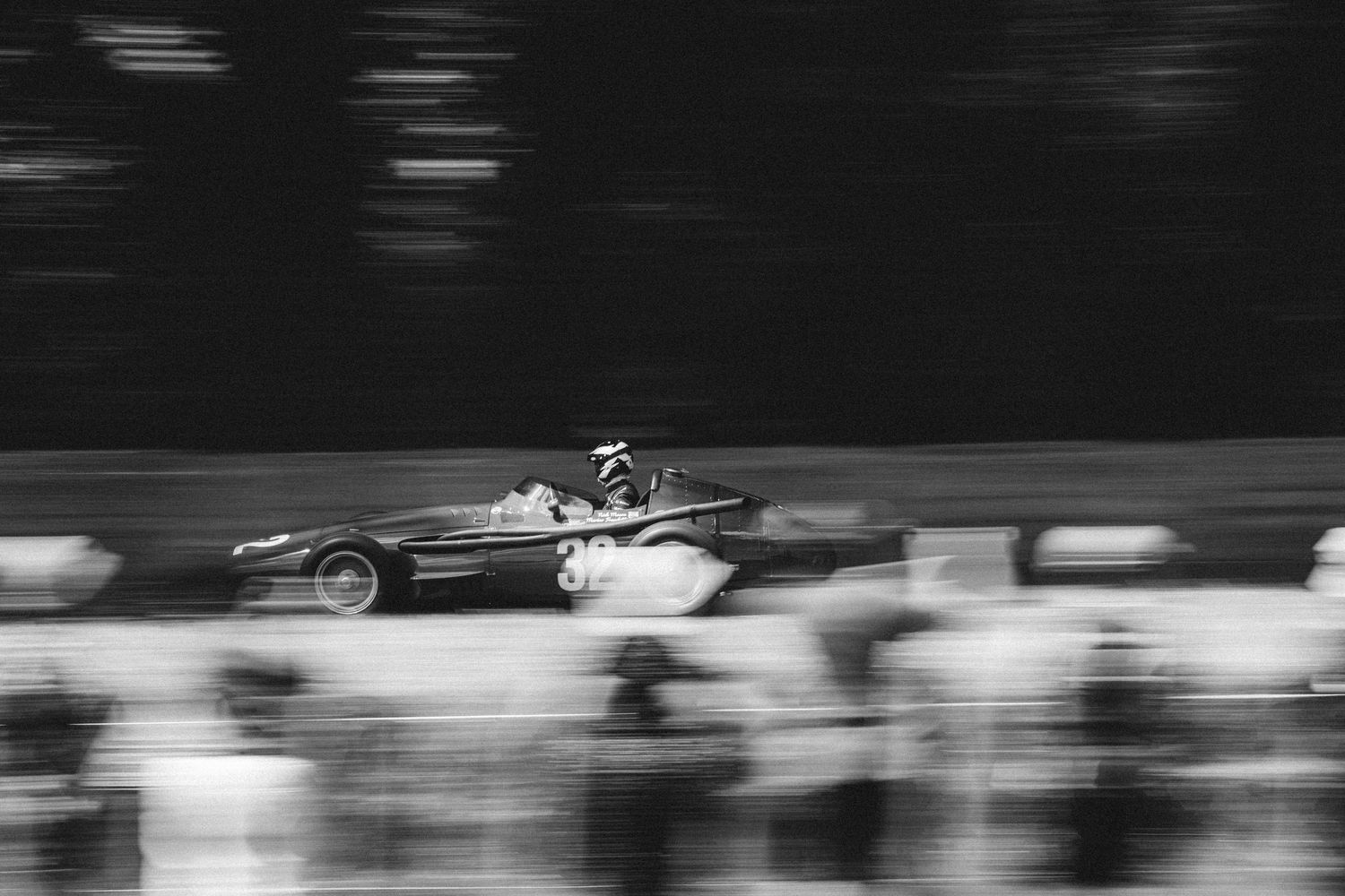 Black and white motion blur shot of racing cars on track.