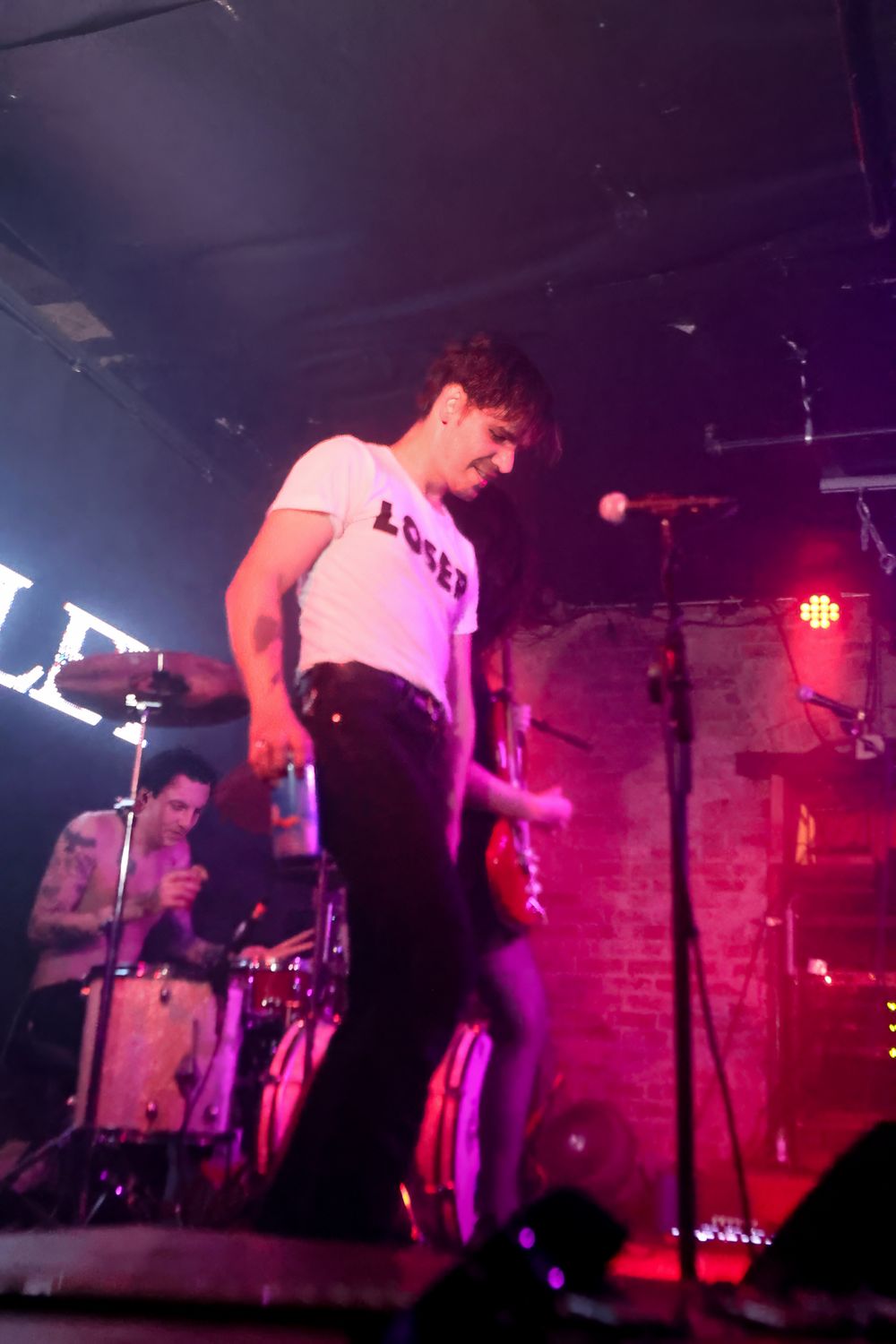 Live music performance on stage with dramatic red and purple lighting creating an energetic concert atmosphere.