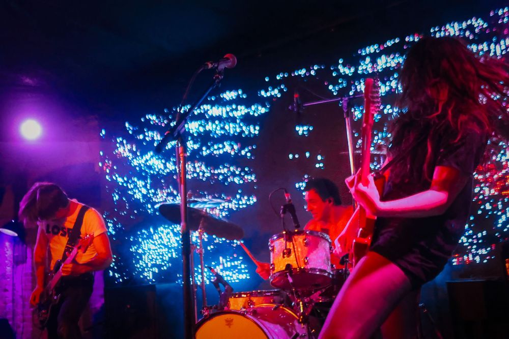 Performers on stage with blue LED lights creating an atmospheric backdrop during a live concert performance.