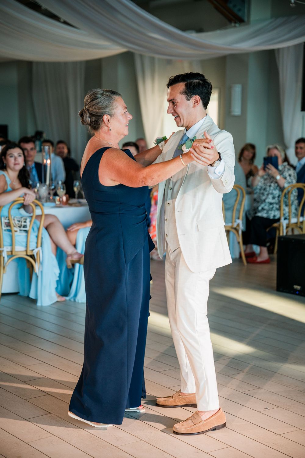 A series of dance photos showing partners in navy and white attire moving gracefully across a reception hall floor.