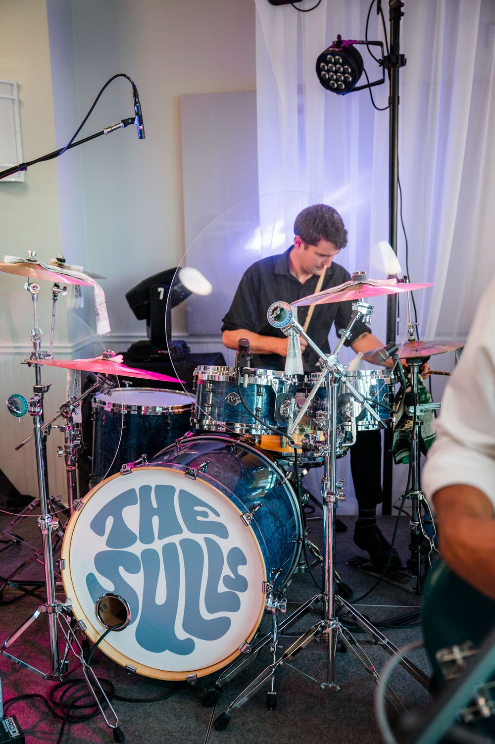 Multiple shots of a drum kit setup in a studio with blue and purple lighting creating an atmospheric mood.