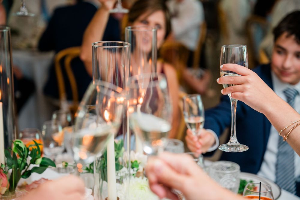 Elegant table setting at a wedding reception with white candles, wine glasses, and floral centerpieces.