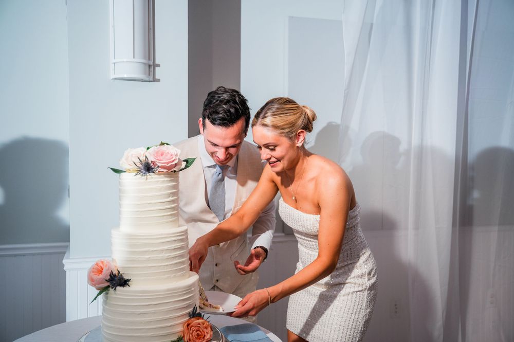 A wedding cake cutting sequence with a multi-tiered white cake decorated with flowers.