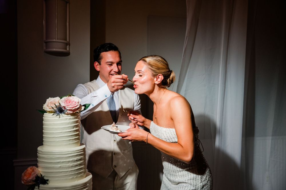 Wedding couple feeding each other cake during their reception celebration.